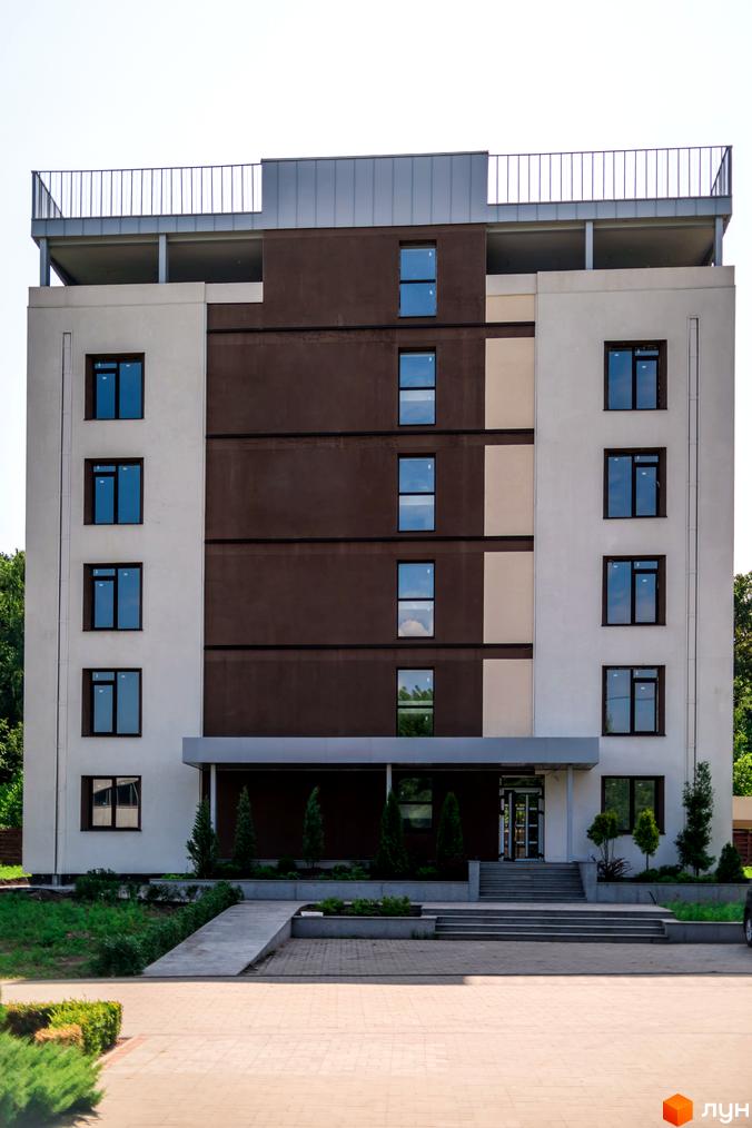 Зовнішній вигляд новобудови ЖК Summerville з п'ятьма поверхами та коричнево-білим фасадом, а також прибудинковою територією з деревами та бруківкою.