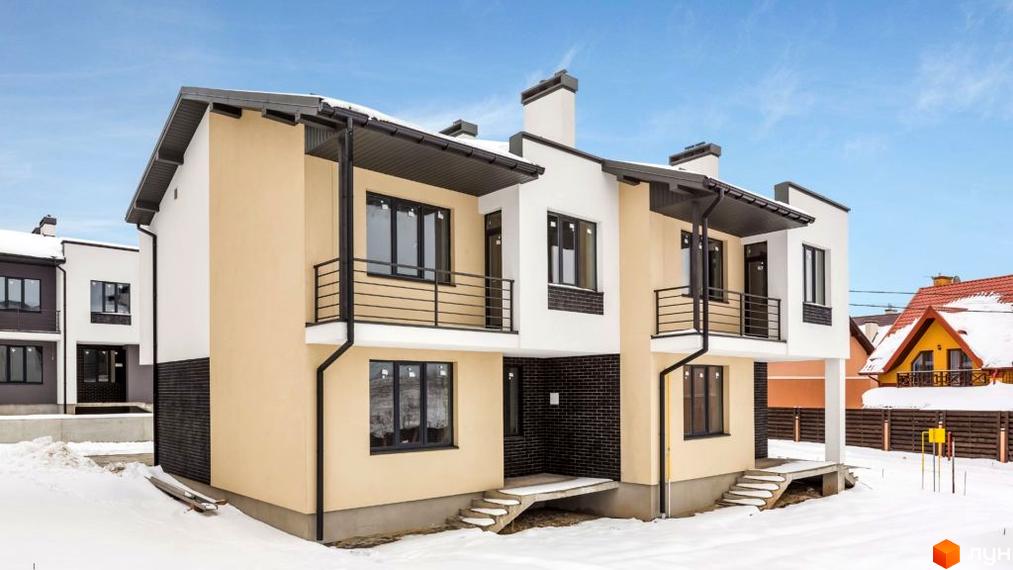 Котеджне містечко КМ Grafit: двоповерхові будинки з бежевим та білим фасадом, чорними вікнами та балконами на тлі зимового пейзажу та блакитного неба.