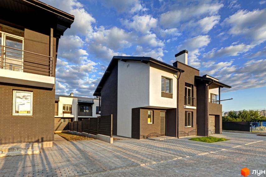 Котеджне містечко Grafit. Двоповерхові будинки з темно-сірими та білими фасадами, балконами та великими вікнами. Територія вимощена бруківкою.