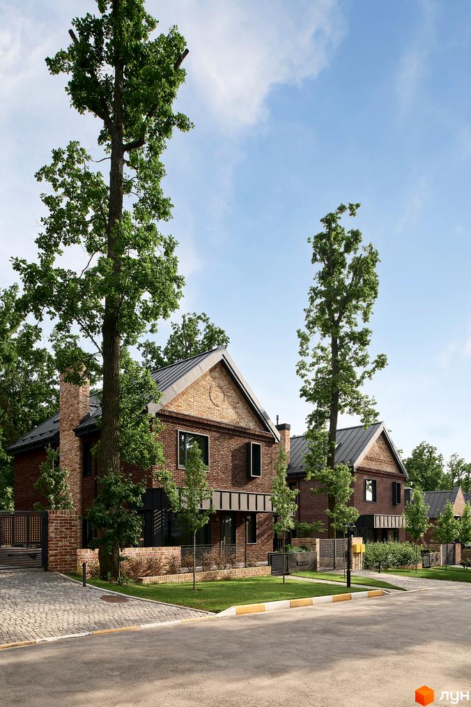 Котеджне містечко Oak Grove Town: цегляні будинки з темними дахами, оточені високими деревами. Доглянута прибудинкова територія з газонами та бруківкою.