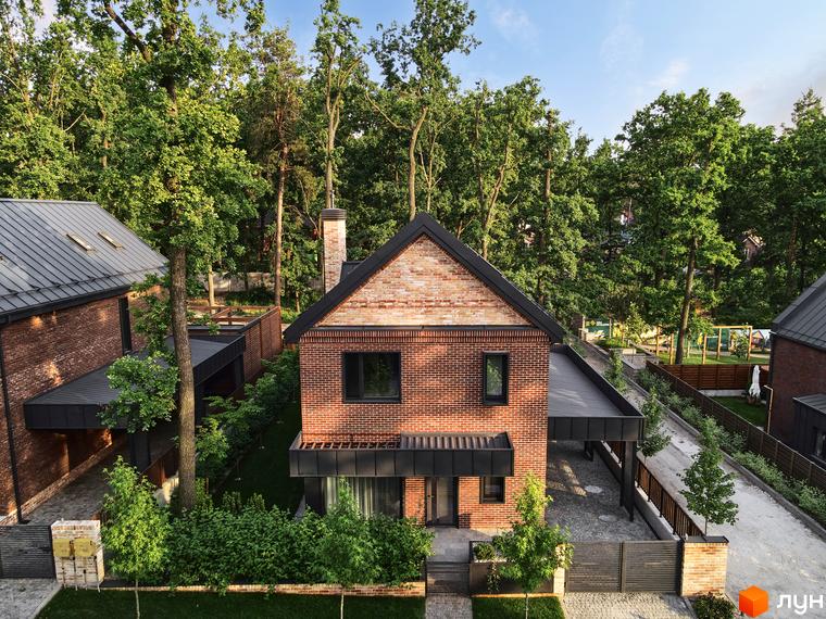 Котеджне містечко Oak Grove Town: цегляні будинки з чорними дахами та вікнами. Навколо багато зелених дерев та доріжки.