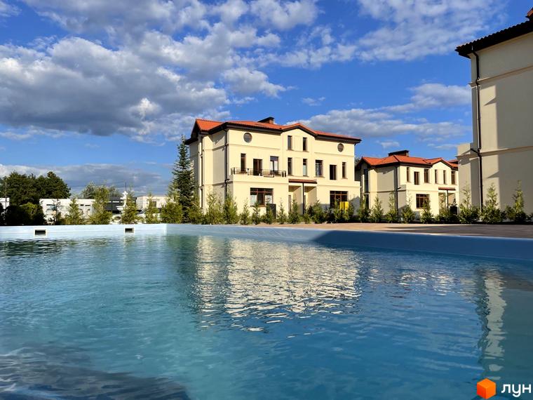 Котеджне містечко КМ Фонтан: світлі фасади будинків з червоними дахами та басейн на прибудинковій території.