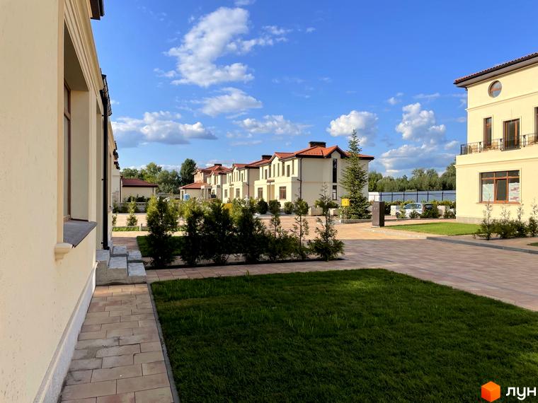 Котеджне містечко Фонтан: фасади будинків з червоним дахом та прибудинкова територія з газоном і доріжками.