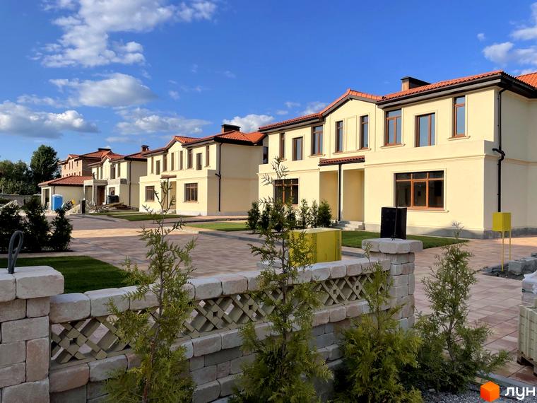 Котеджне містечко КМ Фонтан. Сучасні двоповерхові будинки з червоними дахами та світлими фасадами, розташовані на доглянутій території з бруківкою та зеленими насадженнями.