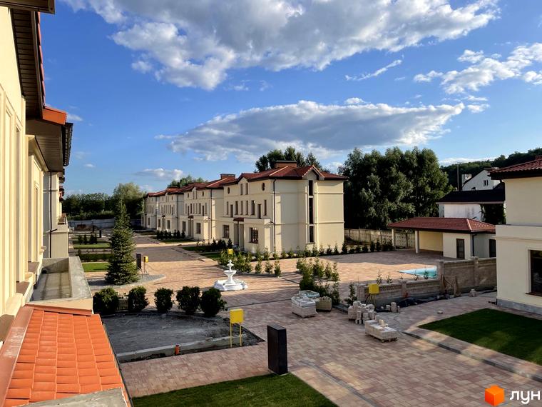 Котеджне містечко КМ Фонтан з елегантною архітектурою та доглянутою прибудинковою територією. На території розташовані будинки, фонтан та зелені насадження.