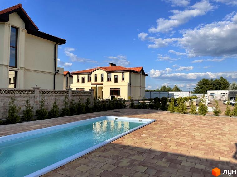 Котеджне містечко Фонтан: двоповерхові будинки з червоними дахами та басейном на території. Прибудинкова територія з бруківкою та зеленими насадженнями.