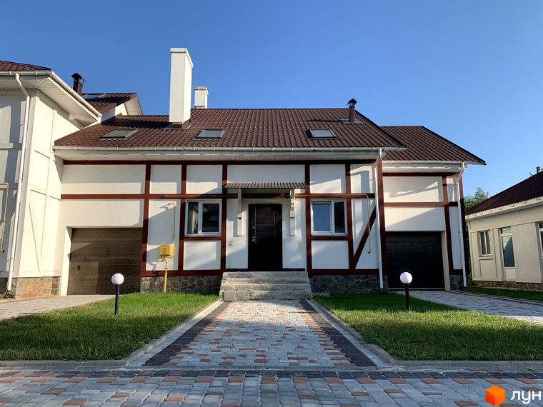 Зображення будинку в Котеджному містечку „Северинівська Перлина“. Двоповерховий будинок з коричневим дахом та білими стінами, вимощеною доріжкою та газоном.