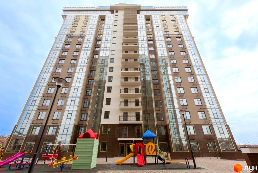 Висотна будівля ЖК Сімнадцята Перлина з великою кількістю вікон. На території розташований дитячий майданчик з гірками та гойдалками.