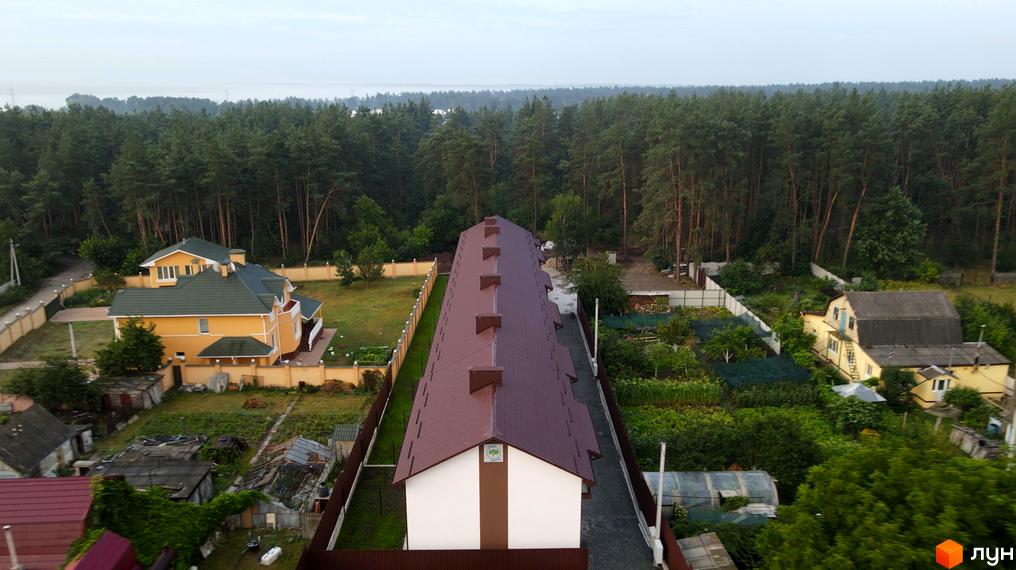 Таунхауси Green Heaven: довгий будинок з коричневим дахом та світлим фасадом, оточений зеленими насадженнями та сосновим лісом.