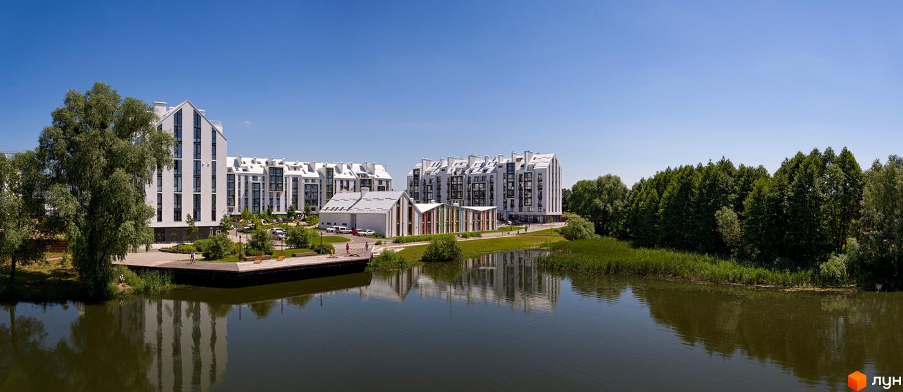 Житловий комплекс City Lake з білими будинками біля озера. Навколо зелені дерева та доглянута територія.