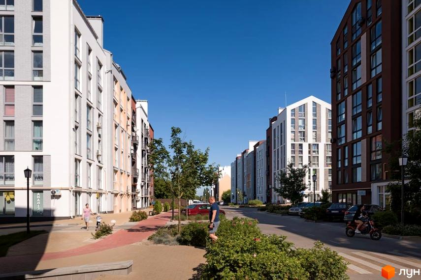 Житловий комплекс Білий Шоколад.Center: фасади будинків з різнокольоровими елементами, вікна, балкони. Територія комплексу з пішохідними доріжками, деревами, місцями для відпочинку.