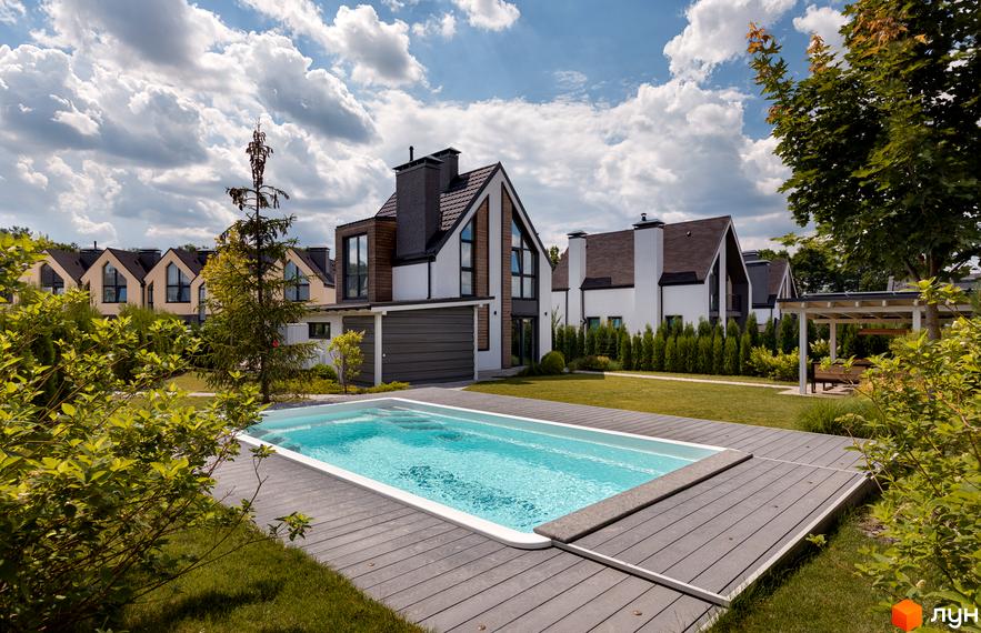 Котеджне містечко КМ VILLAGGO. Будинки з двосхилими дахами та великими вікнами, поруч басейн та зелена ділянка.