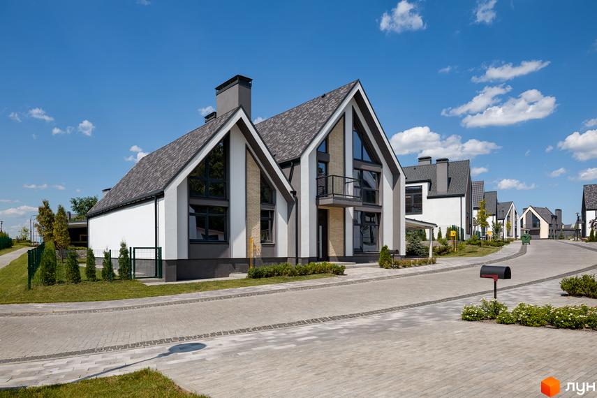 КМ VILLAGGO: котеджне містечко з сучасними будинками з двосхилими дахами та великими вікнами. Прибудинкова територія з брукованими доріжками та зеленими насадженнями.