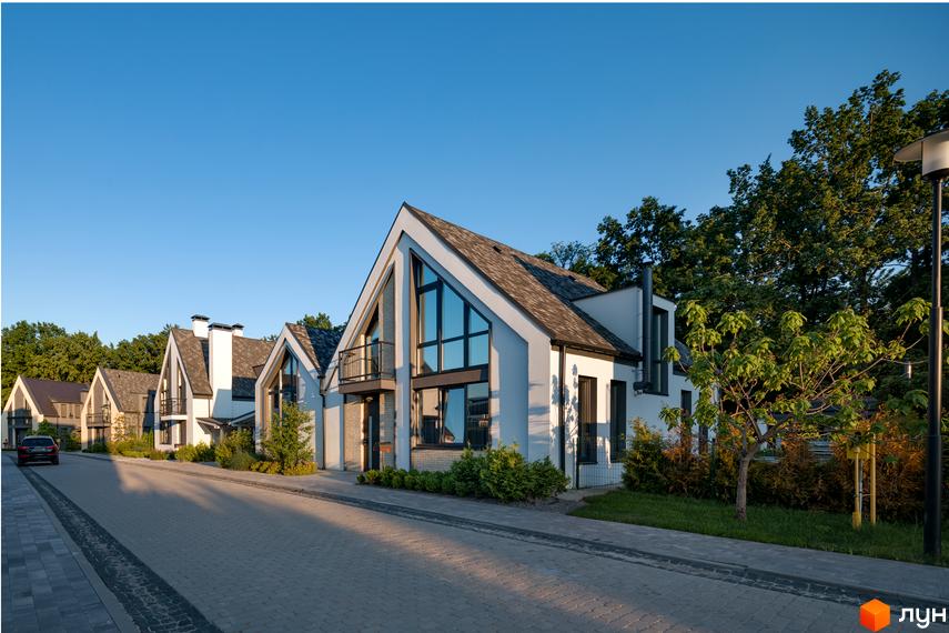 Котеджне містечко КМ VILLAGGO. Сучасні будинки з великими вікнами та гострими дахами, розташовані вздовж бруківки з зеленими насадженнями.