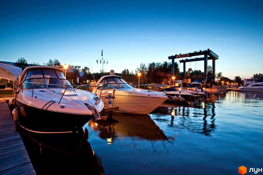 Котеджне містечко КМ BELLAGIO на березі річки з яхтами та човнами у вечірній час. Сучасний комплекс з розвиненою інфраструктурою для комфортного життя.