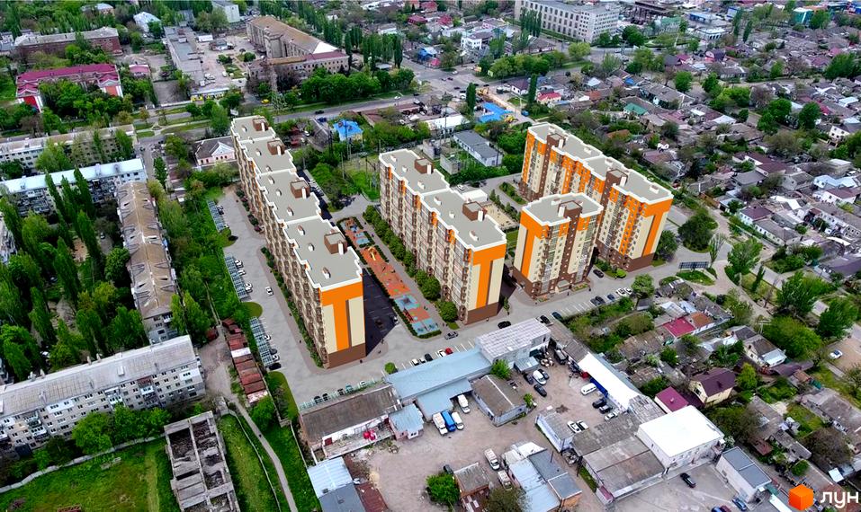 Вид з висоти пташиного польоту на житловий комплекс Громадянський посад з багатоповерховими будинками оранжево-бежевого кольору та прибудинковою територією з дитячим майданчиком та парковкою.