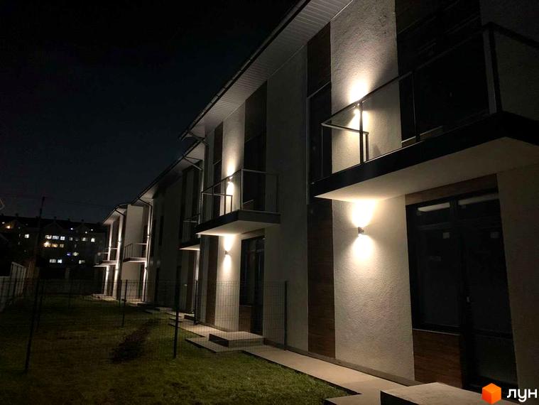 Таунхаус Blestown. Зовнішній вигляд будинків з підсвічуванням вночі, охайна прибудинкова територія з газоном.