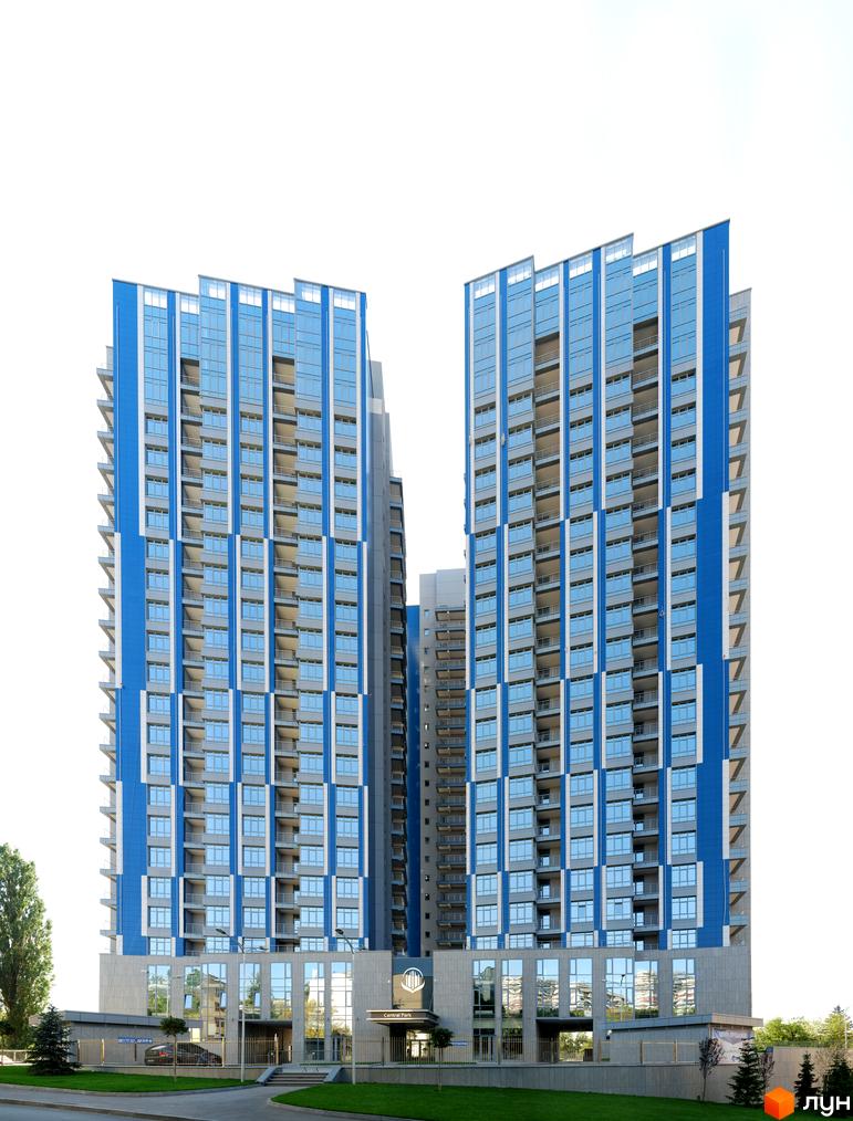 Фасад житлового комплексу Central Park з блакитними та сірими елементами, великою кількістю скління та балконами. Навколо будинку зелена територія з деревами та газонами.