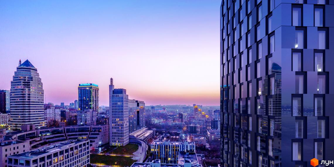 Вид на БФК MAYAK з сучасними фасадами та великою кількістю вікон. Навколо розташовані інші багатоповерхові будівлі міста.