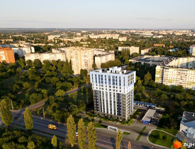 Житловий комплекс Steel House з біло-сірим фасадом та синіми вікнами, розташований серед зелених дерев та міської забудови.