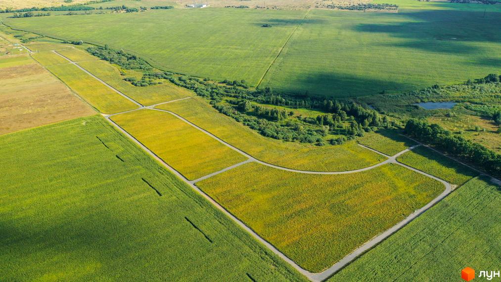 Зображення Котеджного кварталу „Фортеця Колонщини“ з висоти пташиного польоту. Видно поля, дорогу та невеликі будинки.