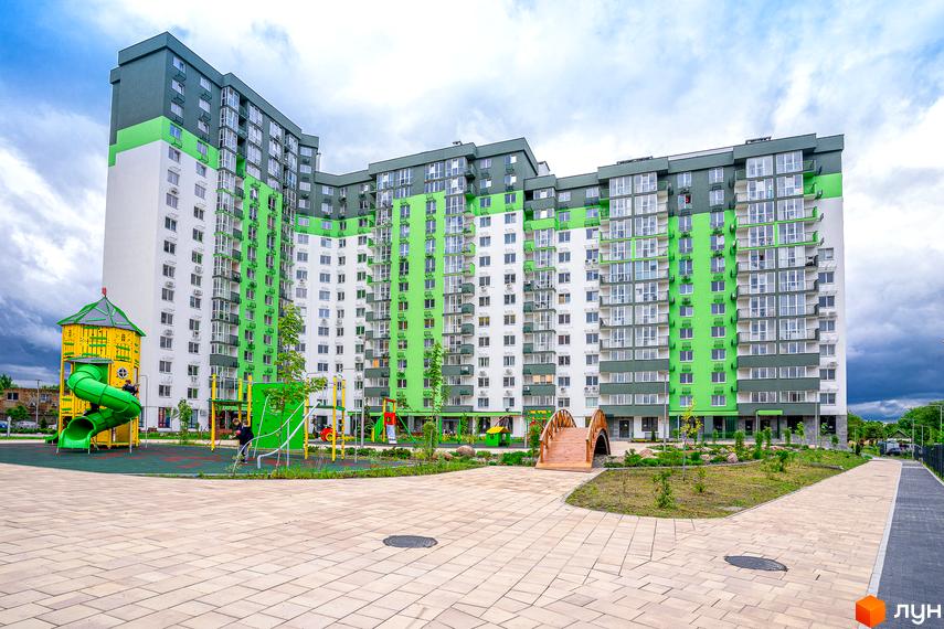 Житловий комплекс Сирецькі сади: багатоповерхова новобудова з яскравим фасадом та дитячим майданчиком. Прибудинкова територія з пішохідними доріжками та зеленими насадженнями.