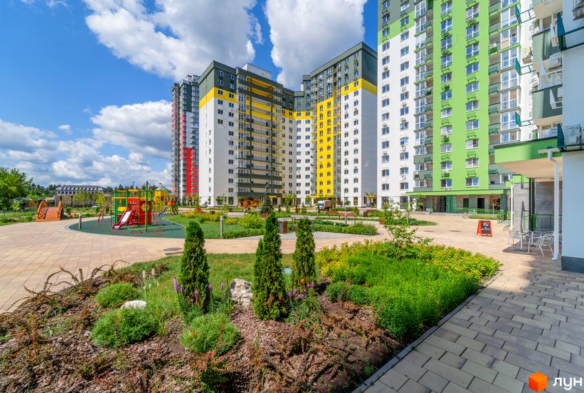 Житловий комплекс Сирецькі сади з яскравими фасадами та дитячим майданчиком. Зелена прибудинкова територія з ландшафтним дизайном.
