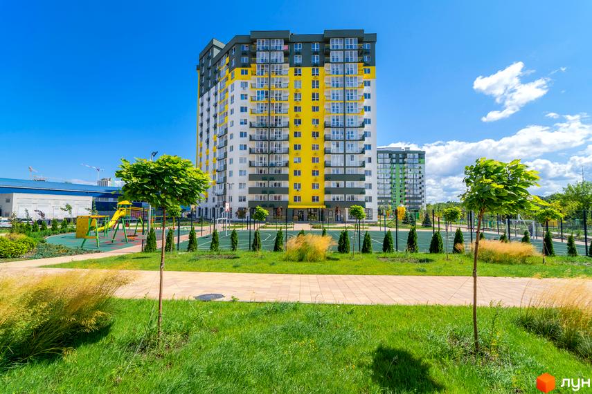 Житловий комплекс Сирецькі сади: висотні будинки з жовтими та білими фасадами, дитячий майданчик та спортивні майданчики на прибудинковій території.