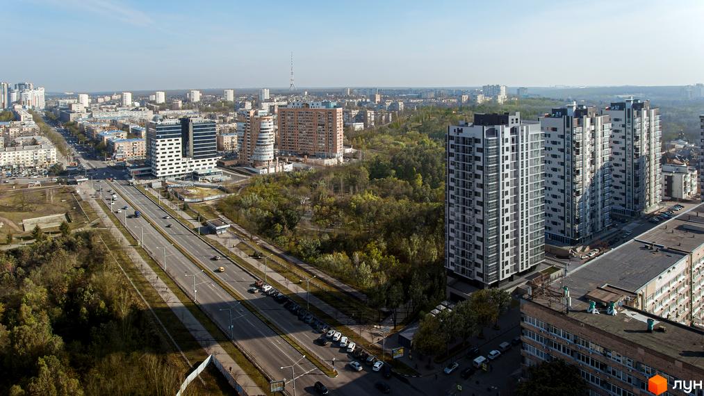 Зображення житлового комплексу Ключ. Висотні будинки з великою кількістю вікон, поруч дорога та зелена зона.