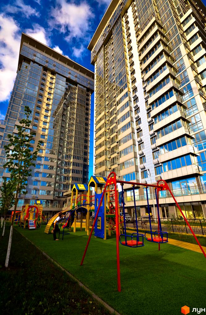 Житловий комплекс RiverStone з сучасними будинками та дитячим майданчиком на прибудинковій території.