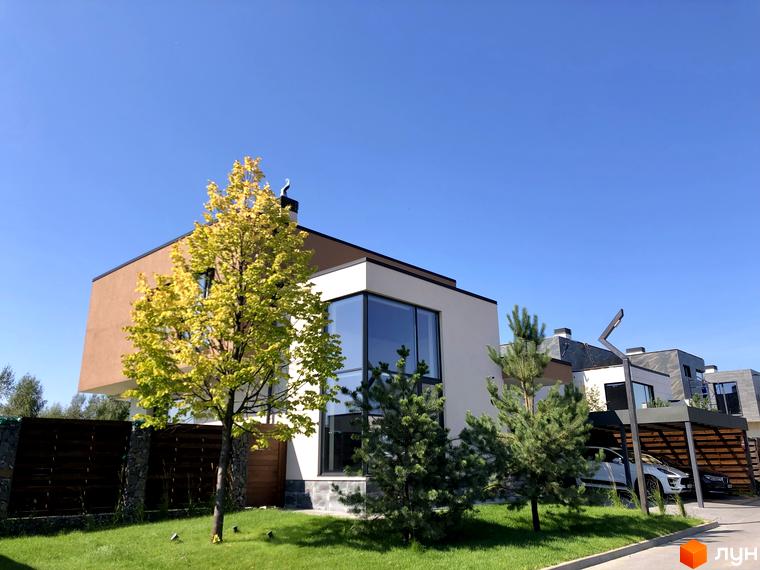 Будинок з великими вікнами та терасою в Котеджному містечку Crystal Forest. На території є дерева та газон.