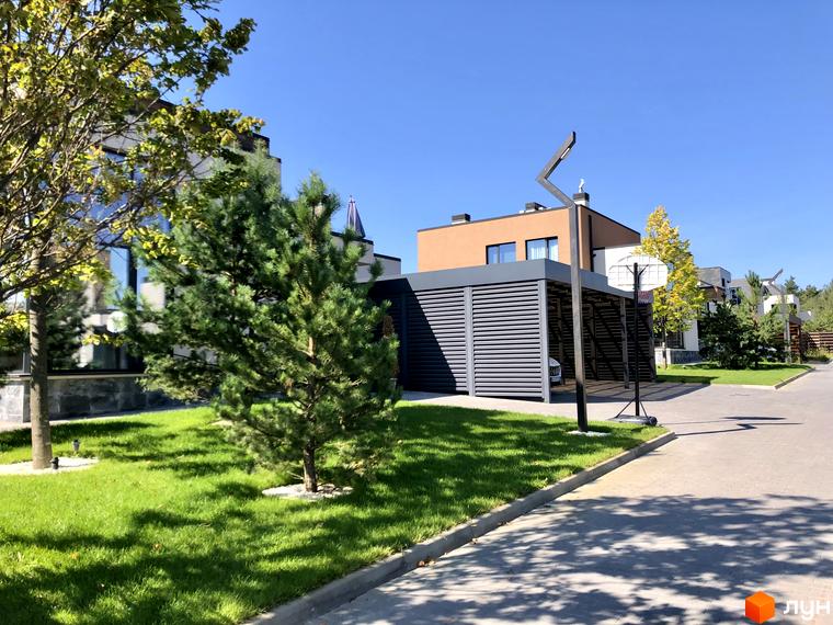 Будинок в Котеджному містечку Crystal Forest з фасадом у світлих тонах. На прибудинковій території газон та дерева.