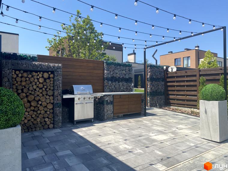 Зона барбекю в Котеджному містечку Crystal Forest. Дерев'яні панелі, кам'яні колони та підвісні ліхтарі створюють атмосферу затишку.