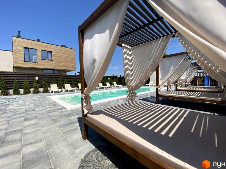 Котеджне містечко Crystal Forest. На фото зображено будівлю з дерев'яним фасадом та зоною відпочинку з басейном і шезлонгами.