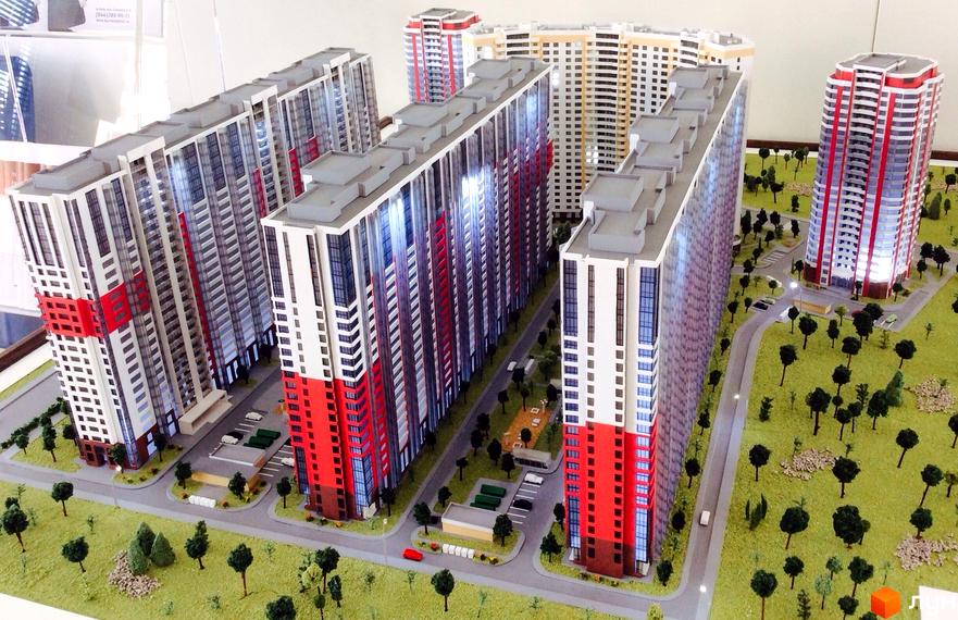 Макет житлового комплексу Позняки-4а з високими будівлями червоно-білого кольору та зеленою прибудинковою територією з деревами. Огляд проєкту новобудови.