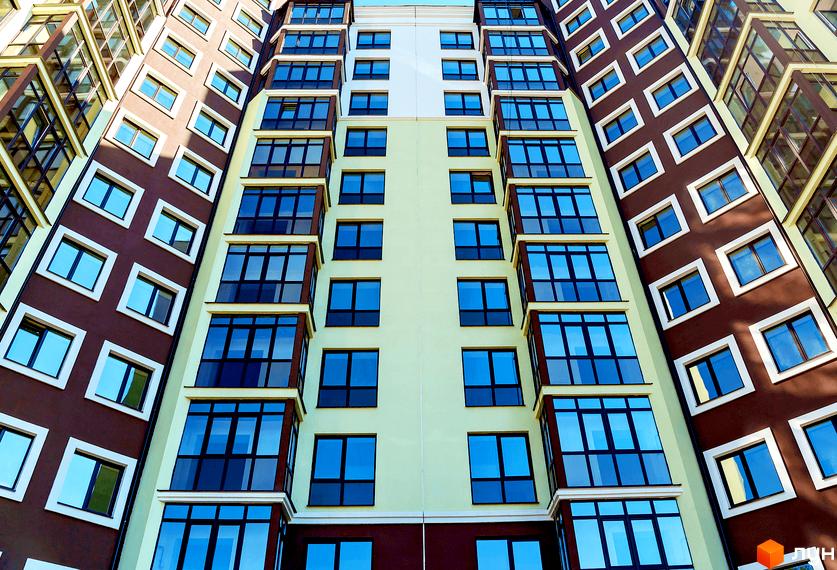 Зовнішній вигляд багатоповерхового будинку. Житловий комплекс Лісова казка з великими вікнами та балконами.