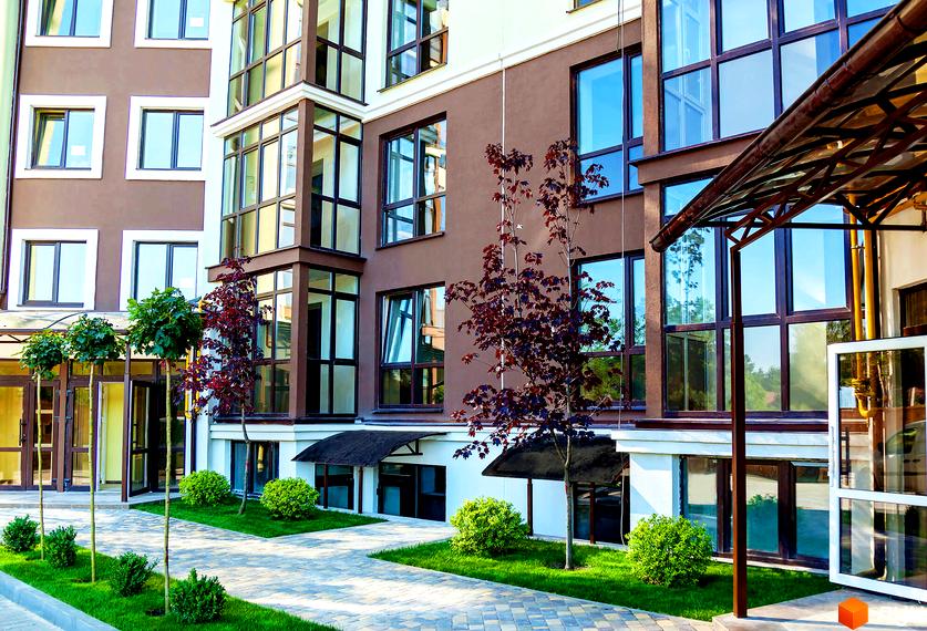 Зовнішній вигляд будинку в Житловому комплексі Лісова казка. Прибудинкова територія з газоном, декоративними деревами та пішохідними доріжками.