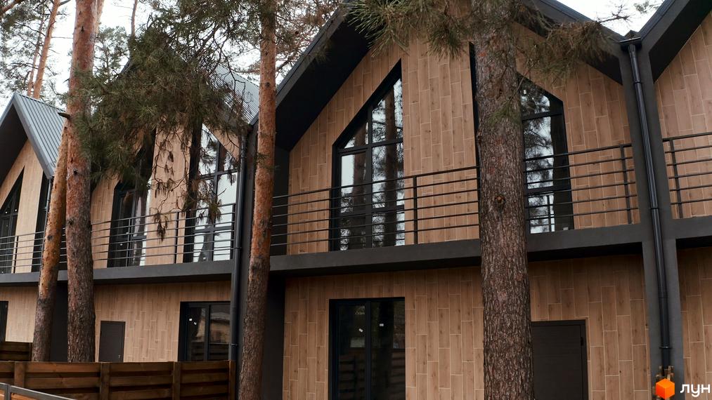 Таунхауси Positano-3 з дерев'яним фасадом та великими вікнами, оточені соснами. Зовнішній вигляд будівель та прибудинкова територія.