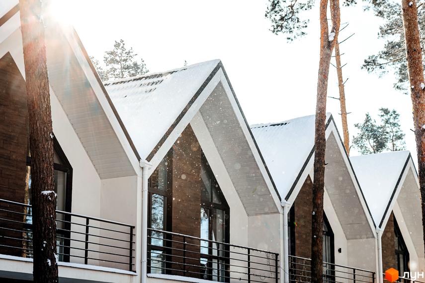 Зимовий вигляд таунхаусів Positano-2 з білими фасадами, панорамними вікнами та снігом на дахах. Поруч ростуть сосни.