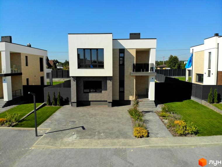 Зображення двоповерхового будинку в Котеджному містечку Full House з великими вікнами та доглянутою територією. Перед будинком висаджені декоративні рослини.