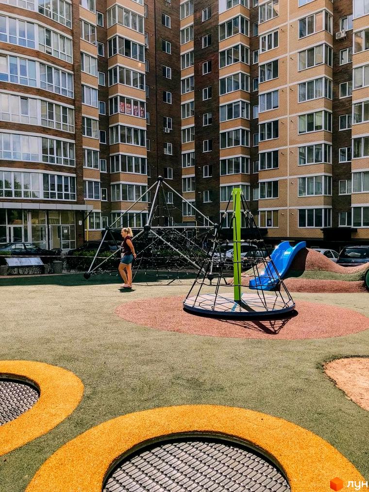 Житловий комплекс Преміум Парк. Зовнішній вигляд будинку та дитячий майданчик з гіркою та сіткою для лазіння.