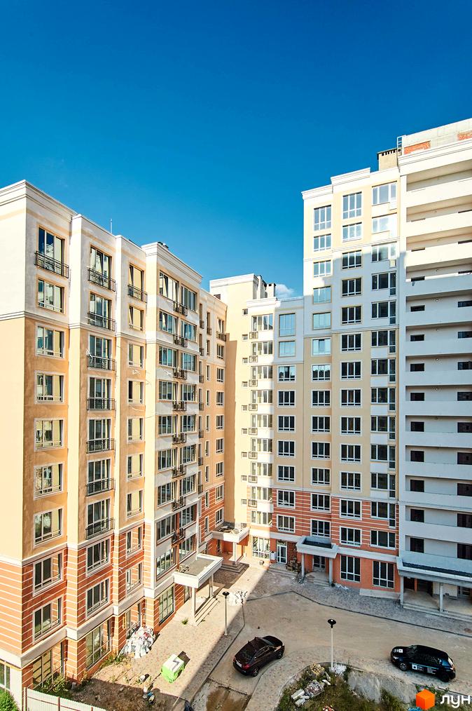 Зображення фасаду та прибудинкової території Житлового комплексу Нові Теремки. Вигляд багатоповерхового будинку з вікнами та балконами.