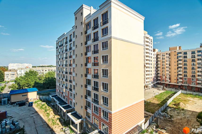 Фото фасаду багатоповерхового будинку в Житловому комплексі Нові Теремки. Навколо будинку видно прибудинкову територію.