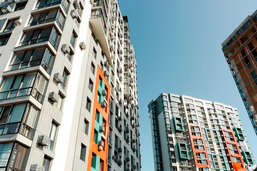 Високі будинки ЖК Crystal Avenue з яскравими фасадами на тлі блакитного неба. Сучасна архітектура та великі вікна створюють привабливий вигляд.