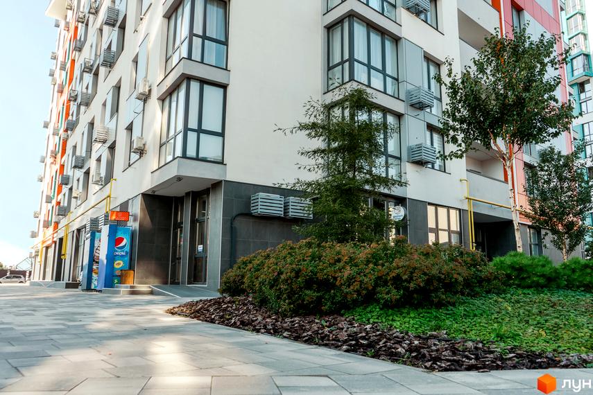 Багатоповерховий будинок Житлового комплексу Crystal Avenue з великими вікнами. Прибудинкова територія має вимощену доріжку та зелені насадження.