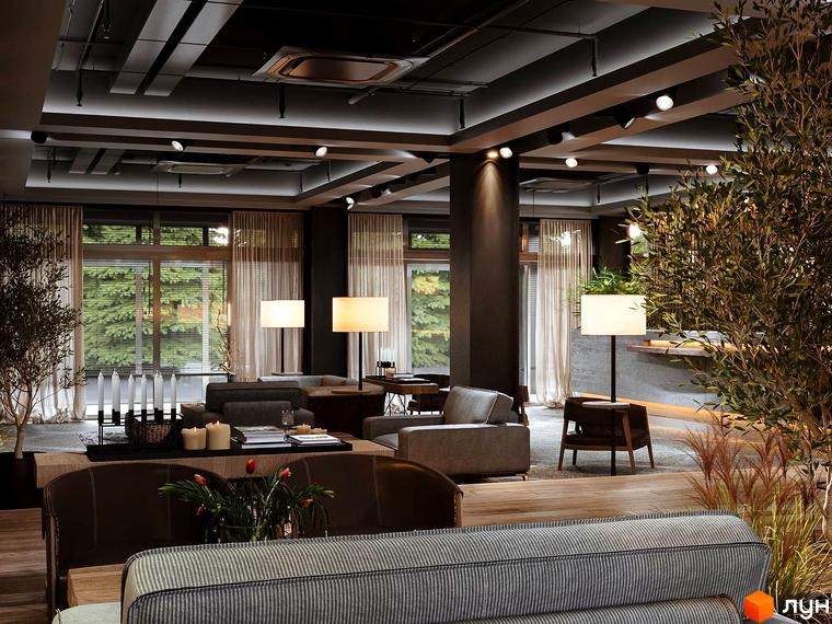 Інтер'єр апарт-комплексу Wood Apartments з диванами, лампами та рослинами на фоні вікон із зеленими деревами.