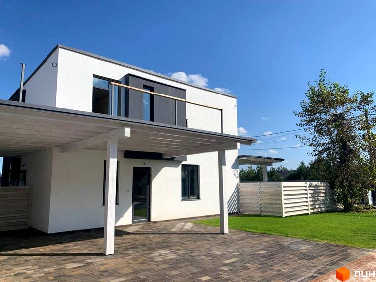 Котеджне містечко КМ Wood Side Village: білий двоповерховий будинок з навісом для авто та зеленою ділянкою. Зовнішній вигляд новобудови та прибудинкової території.