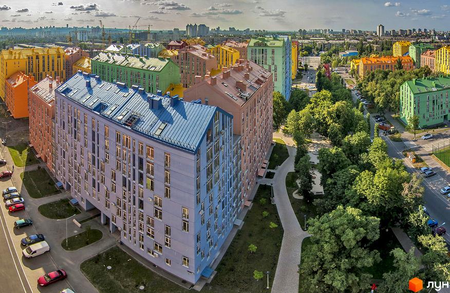 Житловий комплекс Комфорт Таун з кольоровими фасадами та прибудинковою територією з зеленими насадженнями і доріжками.
