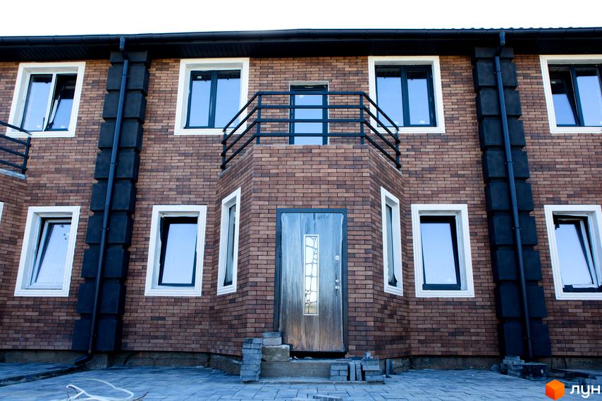 Фасад таунхаусу Nobel Town з коричневої цегли з білими вікнами та чорними водостоками. Перед будинком вимощена тротуарна плитка.