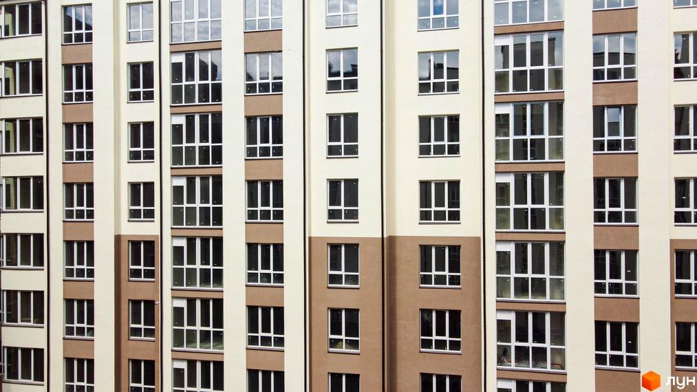 Фасад житлового комплексу Парковий маєток з численними вікнами. Зовнішній вигляд новобудови з коричневими та світлими елементами.